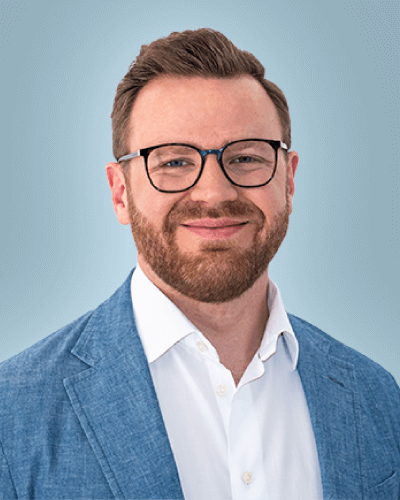 smiling man with beard and glasses wearing white shirt and blue jacket